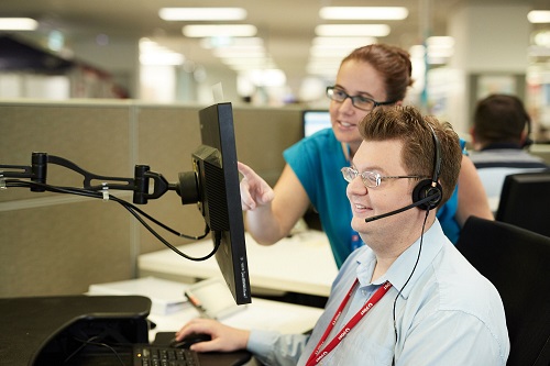 A man uses a computer while a female colleague looks over his shoulder 