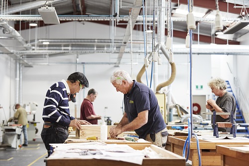 "Two men put together a timber box in an an industrial worksho"