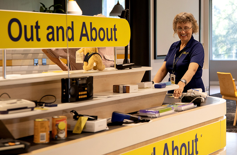 Vision Australia staff member standing in Vision Store surrounded by assistive products and technology in Out and About section.