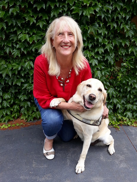 Image shows Di kneeling down outside with her dog guide