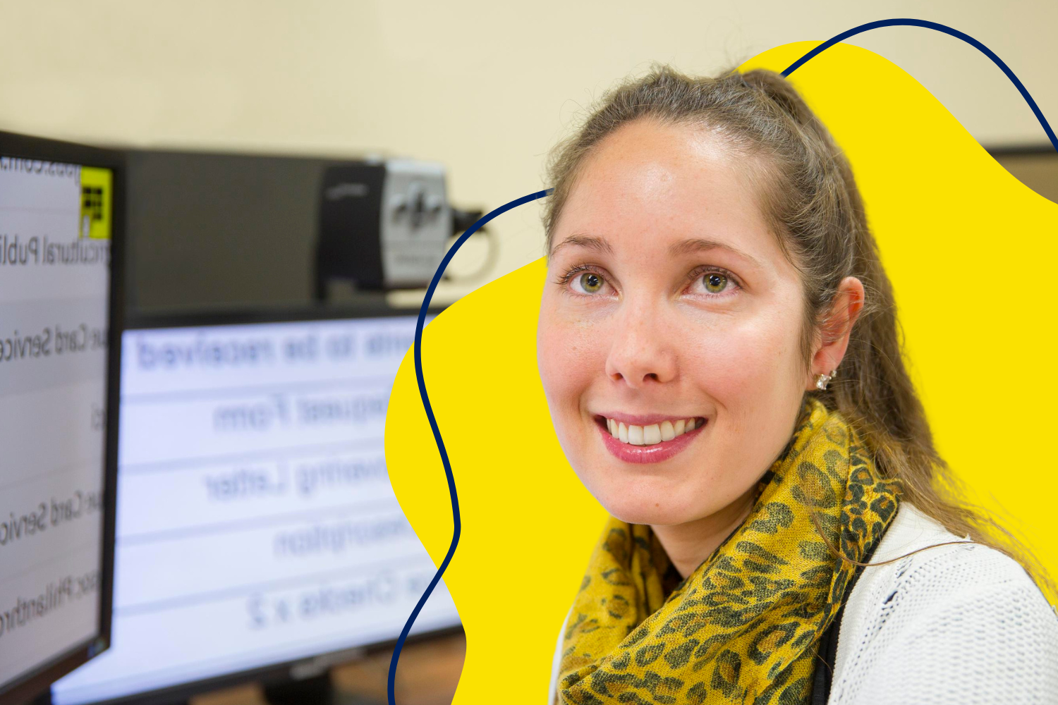 A young smiling woman sits in front of her work computer, with the screens zoomed in to make the text bigger. A yellow curved graphic with swerving navy lines is behind her.