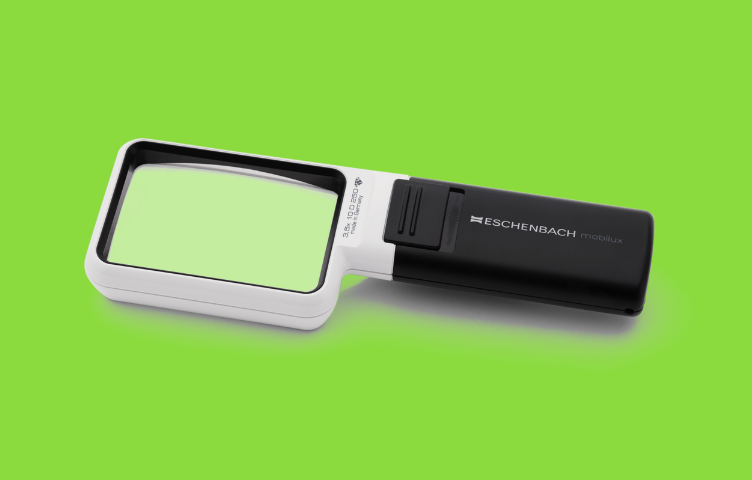 A handheld magnifier with LED lights sits against a bright green background.