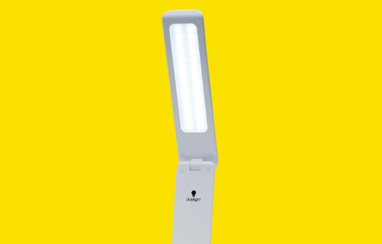 A sleek, modern adjustable lamp sits against a bright yellow background.