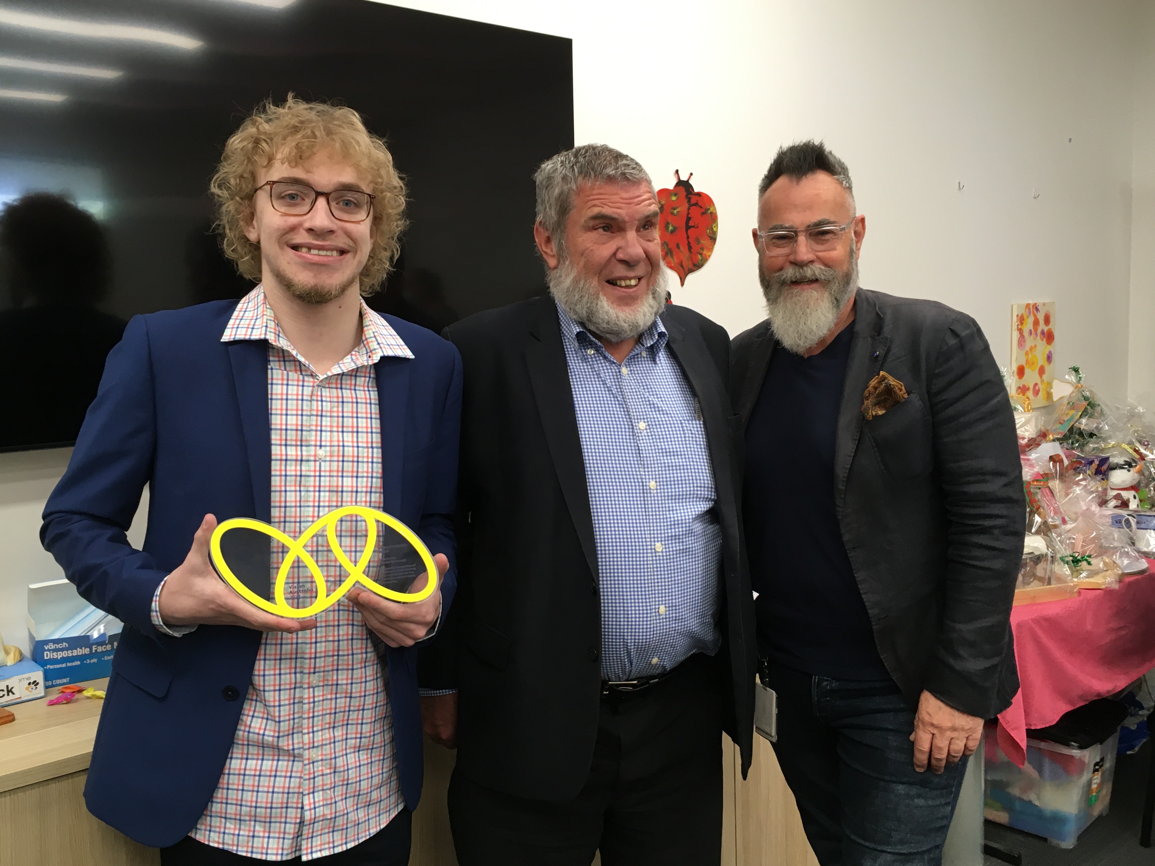 "Gabriel holding his Vision Australia Award next to Bill Jolly and Graeme Craig"