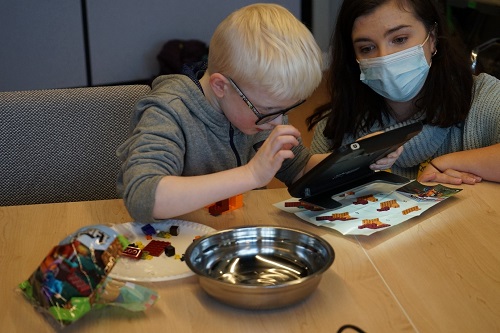 A young boy uses a handheld magnifier to read Lego instructions