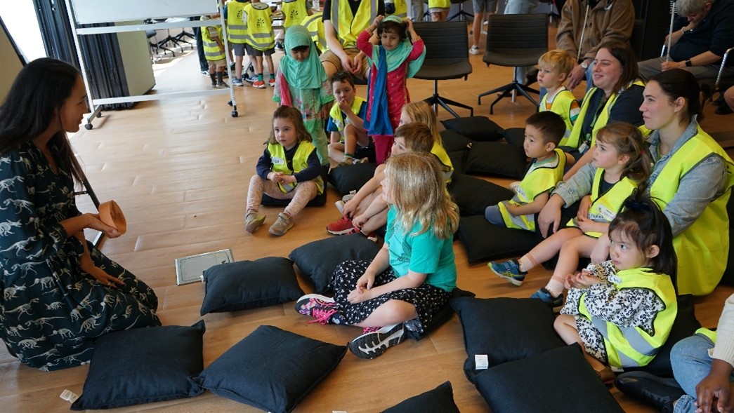 "Adele shows a group of children a dinosaur footprint cast."