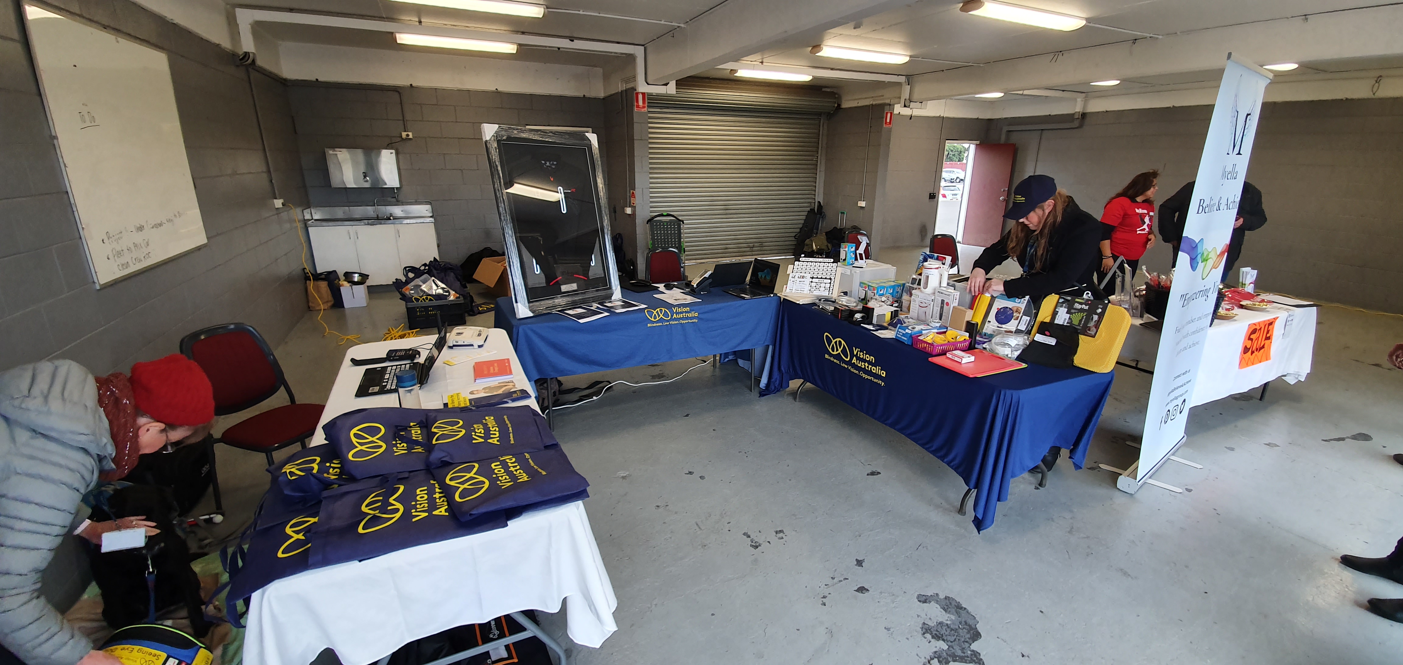 "Inside Vision Australia's booth. Three tables with Vision Australia information and products are on display."