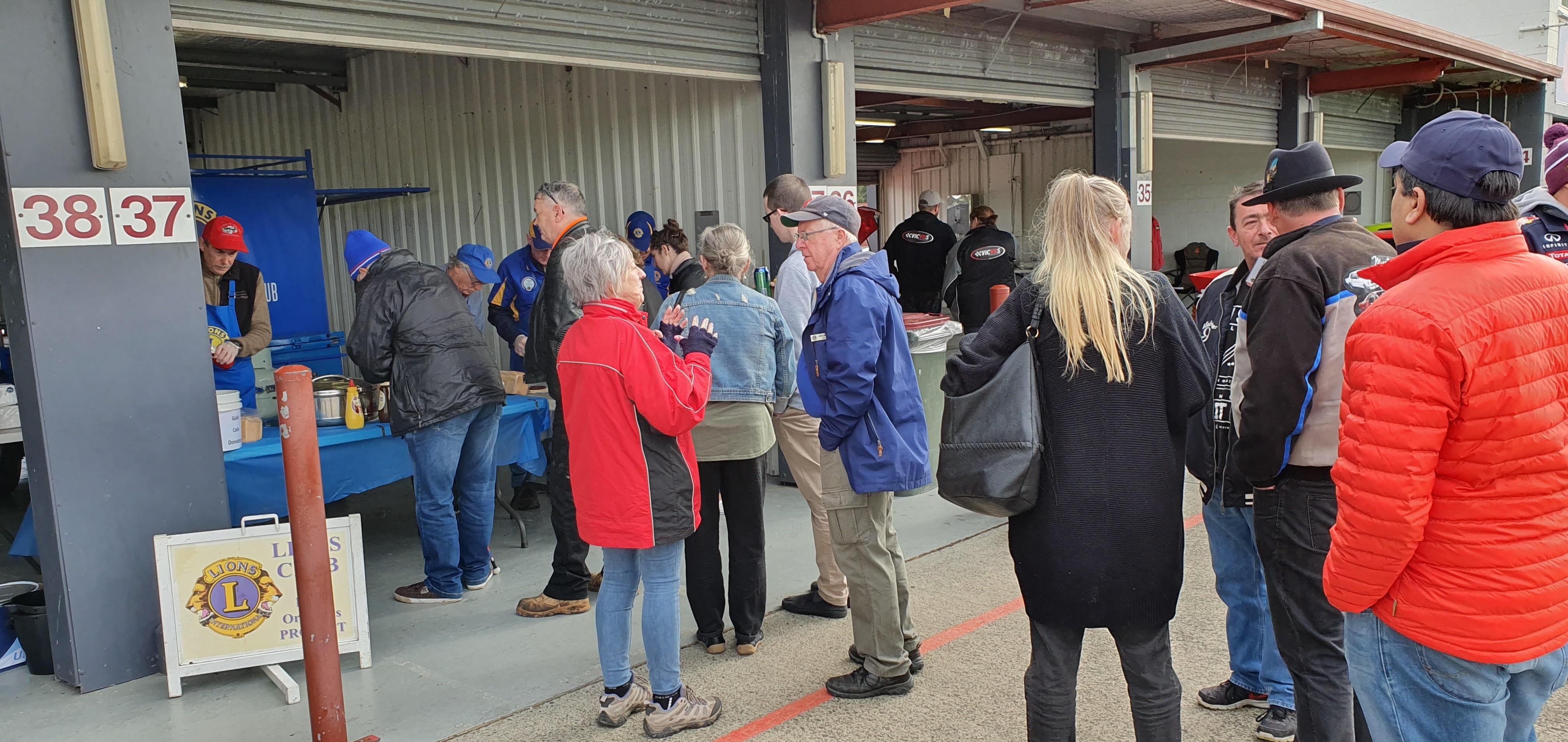 "Warrandyte Lions Club members serve a sea of people with sausages and hamburgers."