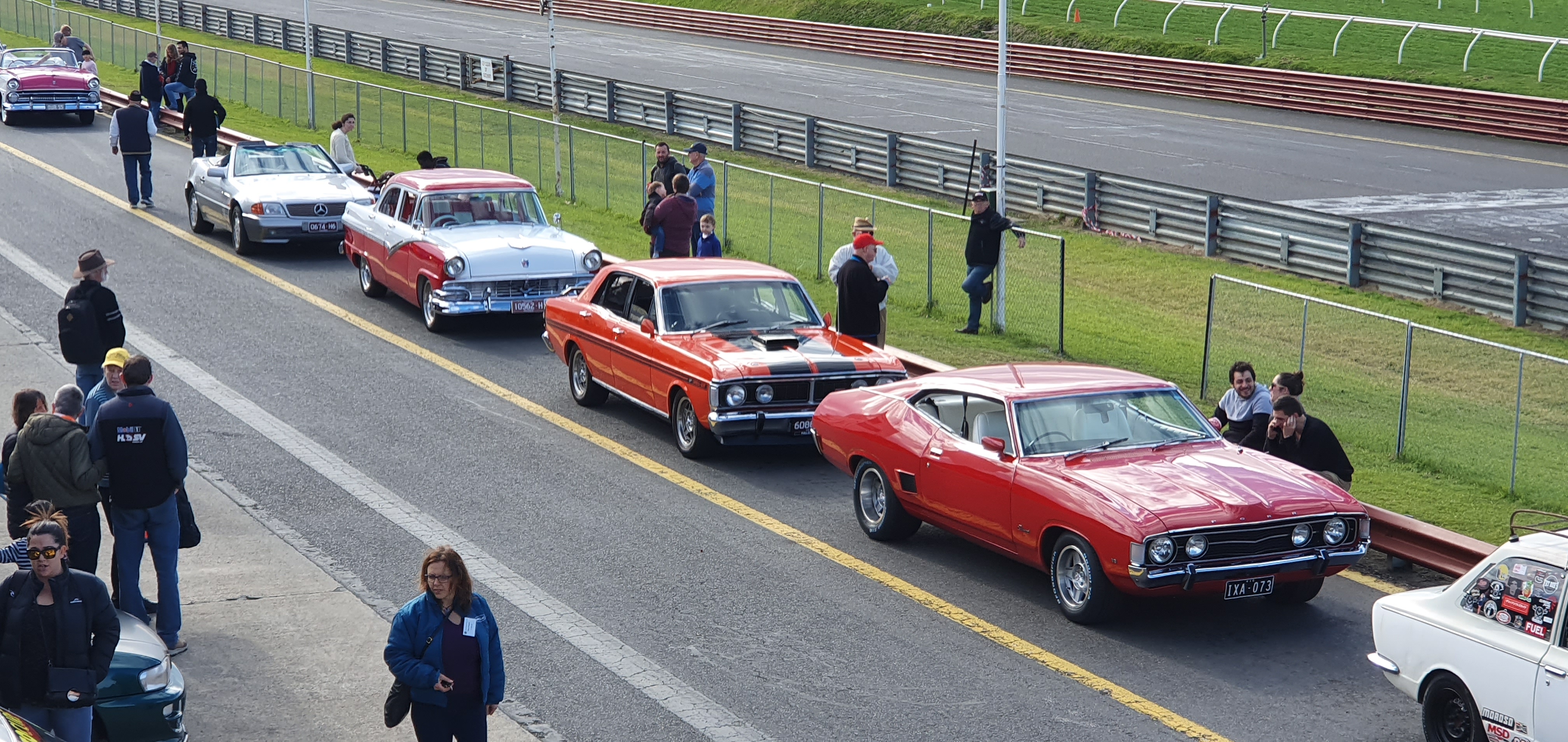 "A row of classic cars lined up ready to go for a joyride. A combination of cars from the 50's, 60's and 70."