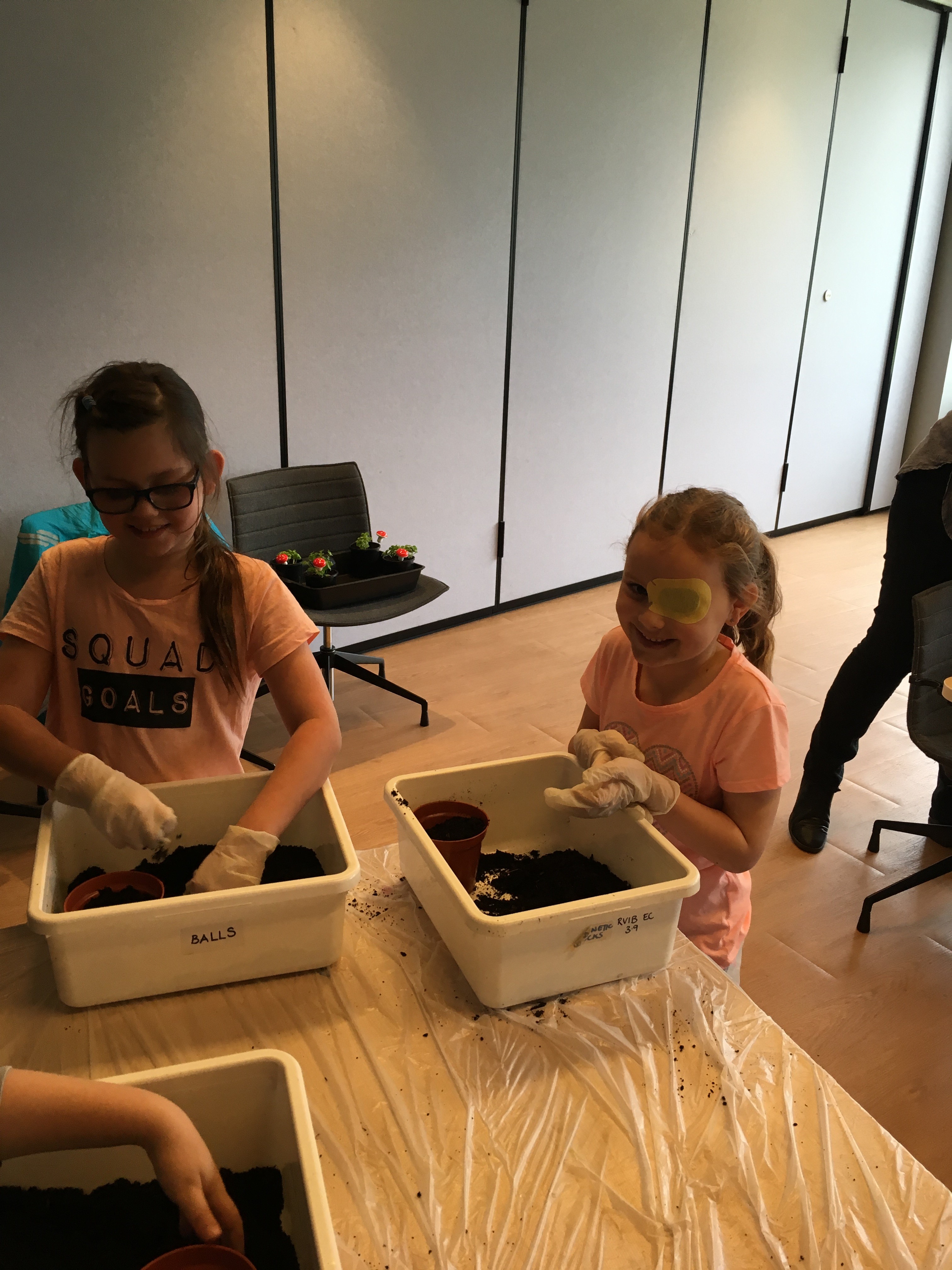 Two girls with pot plants decorating the pot and planting their flowers