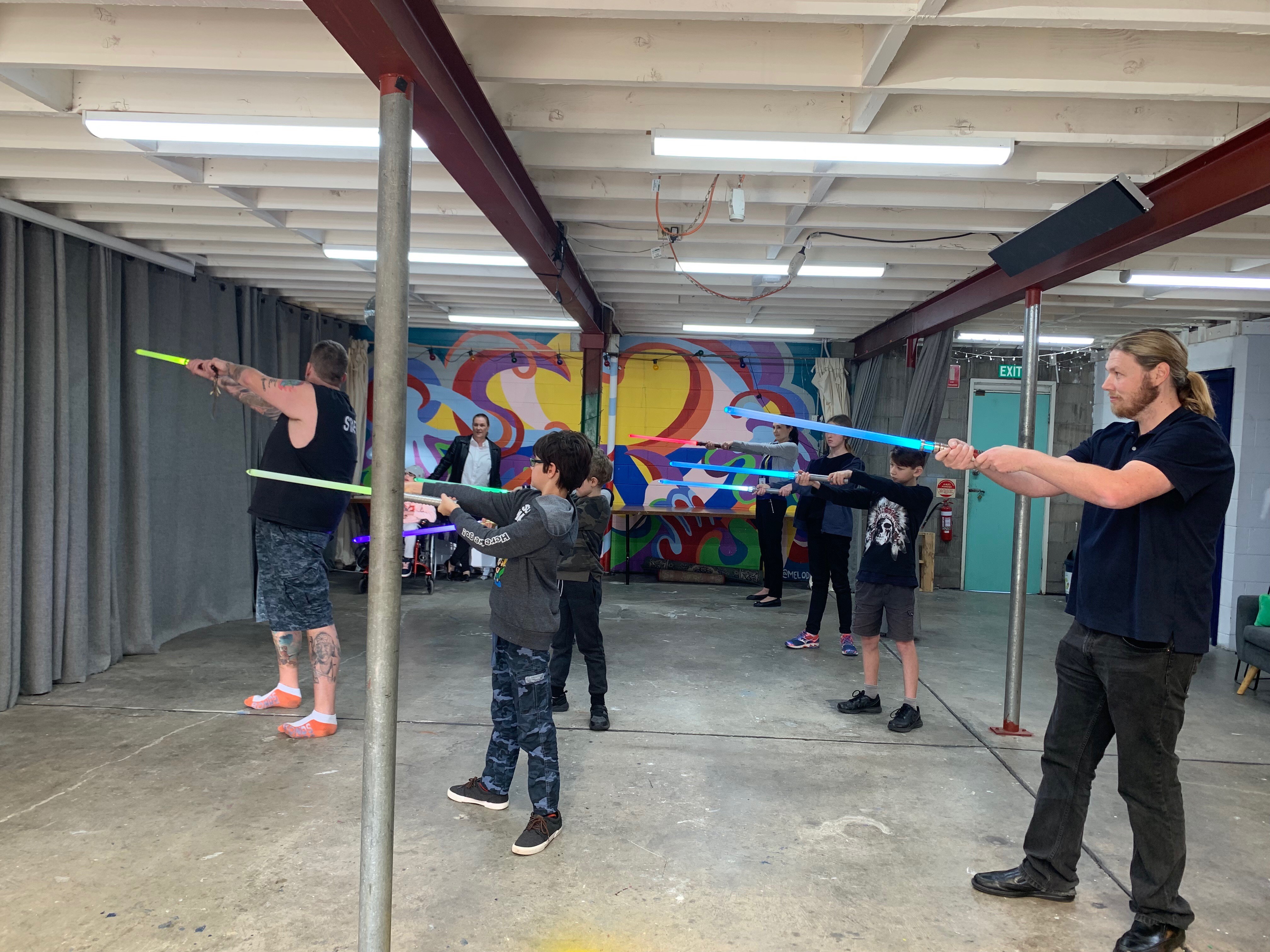 Kids practicing their light saber technique with teachers from the Academy