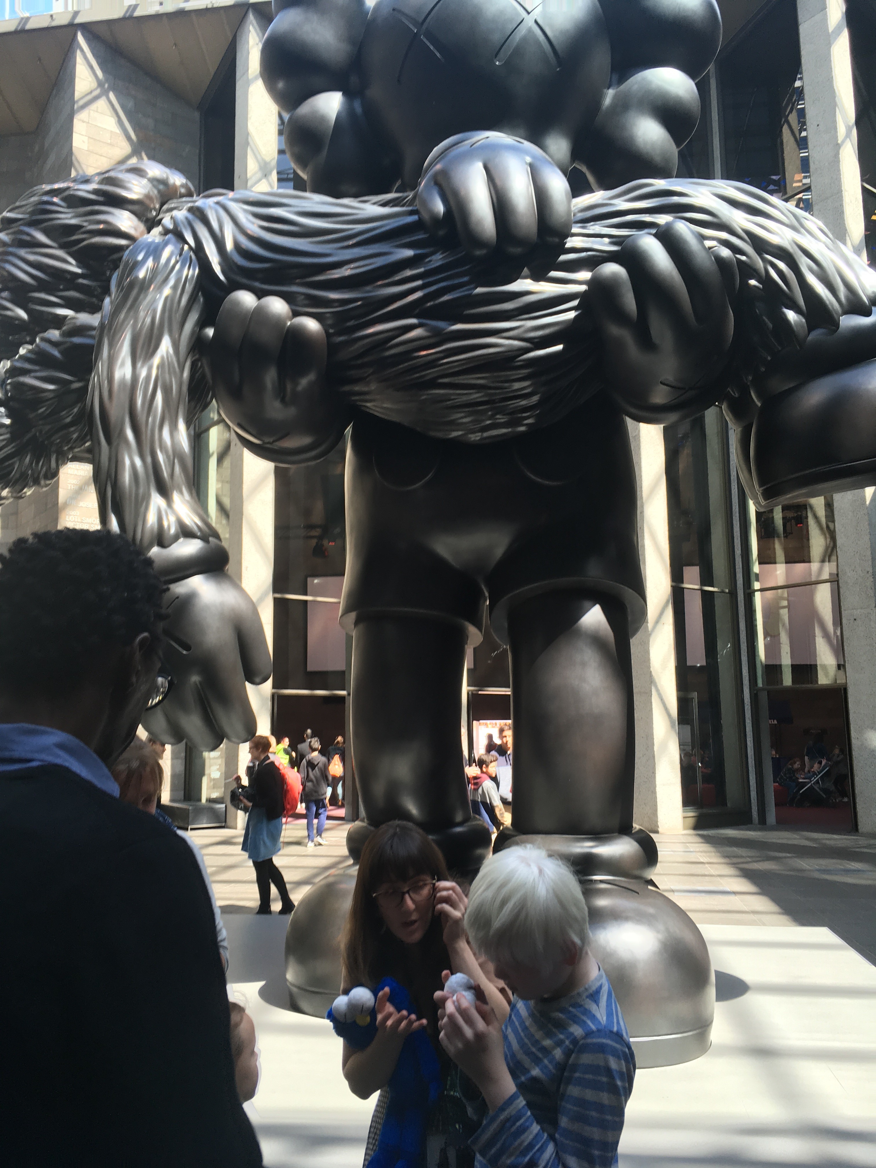 School holiday group at NGV in front of a sculpture of a metal giant