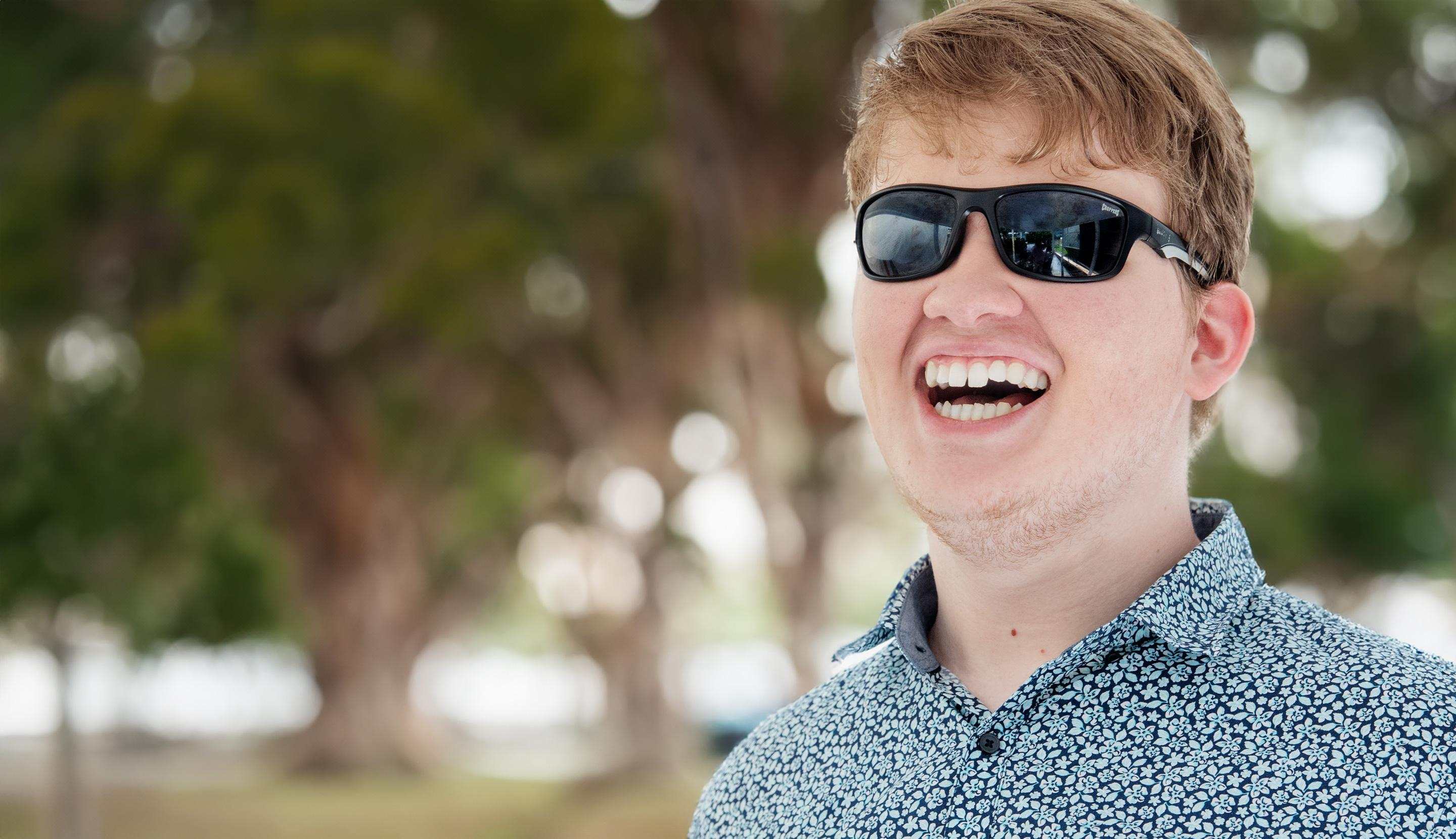 A man with sunglasses smiling widely