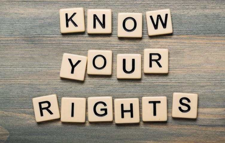 The words ‘know your rights’ is written out in Scrabble tiles on top of a wooden plank.   