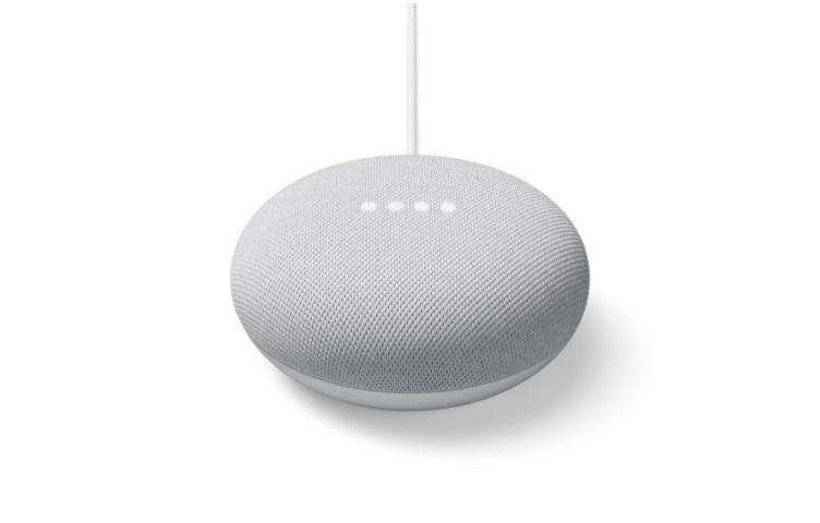 A white smart speaker with four LED dots on top, connected by a cable.