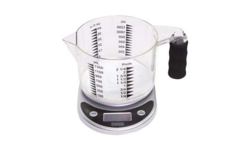 A clear measuring jug with bold black markings sits on a digital scale with a black handle.